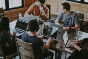 Startupteam granskar data och kod på bärbara datorer runt ett bord